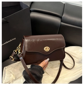 Détail du sac carré en cuir brillant marron foncé avec fermoir rotatif doré et bandoulière