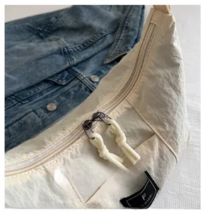 Detail of beige wrinkled nylon tote showing smooth double zippers and branded woven label