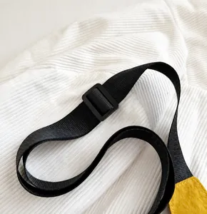 Détail de la bandoulière noire réglable avec boucle sur un sac en nylon jaune vif