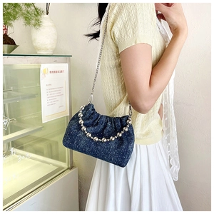 Detail of vintage denim drawstring bucket bag with silver bead handle and polka dot texture