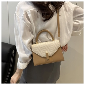 Close-up of minimalist two-tone crossbody bag with woven flap and tan leather base