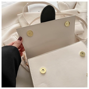 Détails des fermoirs magnétiques sur le sac à rabat en cuir beige et métal doré