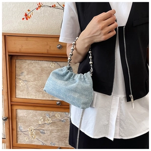 Close-up of light blue sequined cloud bag with silver bead handle and chain strap