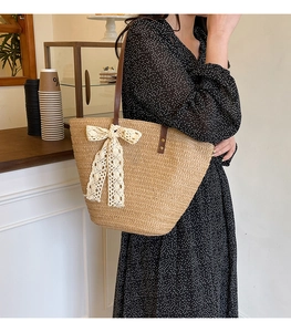 Close-up of woven straw tote bag with large lace bow and brown leather shoulder straps