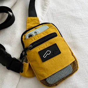 Détail d'un sac bandoulière jaune en nylon avec fente pour téléphone et poche filet noire
