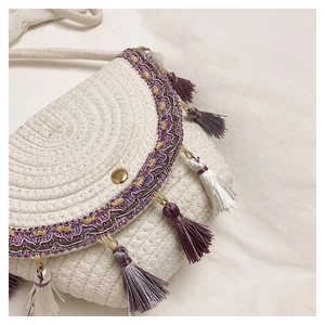 Dettaglio borsa da spiaggia intrecciata con nappe viola e ricami eleganti