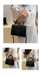 Close-up of minimalist black handbag with gold metal clasp and textured grain leather finish