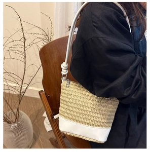 Détail d'un sac porté épaule en paille tressée avec base en cuir blanc et lumière douce