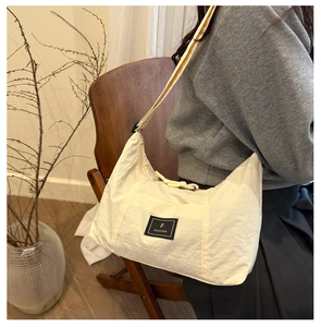 Detail of a cream-colored nylon hobo bag showing fabric texture and adjustable shoulder strap