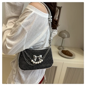 Détail du sac en denim noir avec paillettes argentées, chaînes et pendentifs nœuds