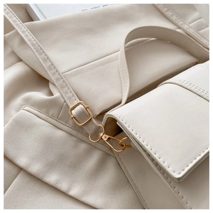 Gros plan du cuir crème avec boucles dorées et coutures soignées sur un sac à main