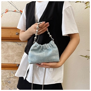Detail of blue denim bucket bag featuring silver bead handle and sparkling sequins texture