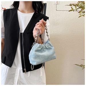 Detail of light blue denim bucket bag with silver bead handle and chain strap