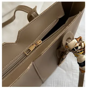 Detail of smooth golden zipper and decorative silk scarf on a brown leather tote bag