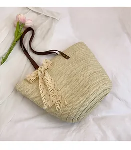 Close-up of woven straw tote bag with brown leather handles and a cream lace bow accent