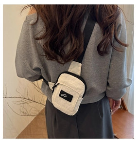 Vista posteriore del modello con borsa a tracolla in nylon crema e cinturino regolabile