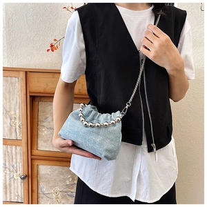 Detail of light blue denim bucket bag with silver bead handle and chain strap