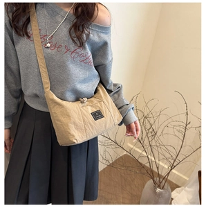 Detail of khaki minimalist tote bag featuring a black woven logo and wide shoulder strap
