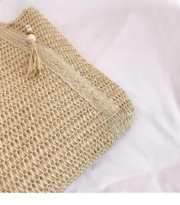 Detail of hand-woven straw bag texture with beige tassels and white wooden beads décor