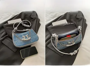 Macro detail of light blue tweed shoulder bag showing silver bow and pearl chain handle