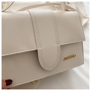 Détail du sac en similicuir crème avec logo JINGPIN doré et surpiqûres élégantes