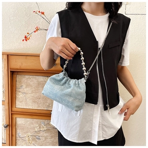 Detail of light blue denim bucket bag with silver bead handle on female model