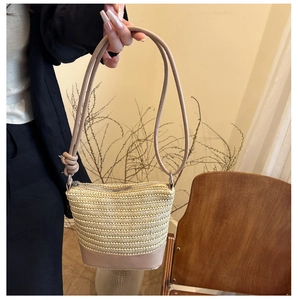 Détail du sac seau en paille tressée avec base en cuir et fermeture éclair