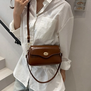 Sac bandoulière carré marron rétro avec fermoir doré porté par un mannequin chic
