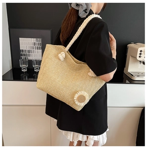 Dettaglio della borsa tote in paglia intrecciata con corda di cotone e fiore all'uncinetto