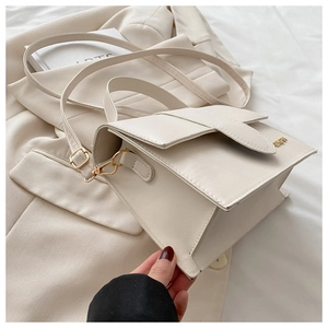 Détail du sac à main crème avec logo doré et finition en cuir synthétique texturé
