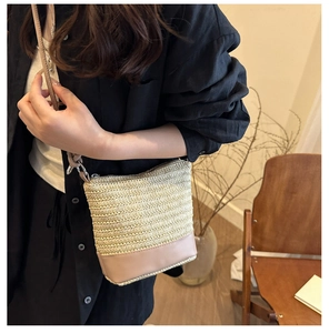 Sac bandoulière en paille tressée avec bordure en cuir marron porté par un mannequin