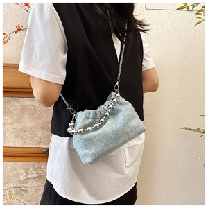 Detail of light blue denim bucket bag with silver bead handle and chain on model