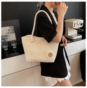 Dettaglio della borsa tote intrecciata beige con decori floreali e spessi manici in corda
