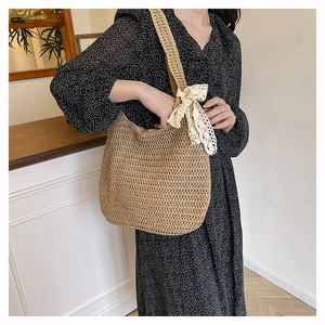 Close-up of woven straw tote bag with delicate yellow lace bow detail on handle