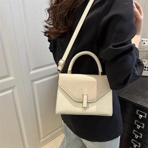 Minimalist beige crossbody bag featuring woven flap detail and golden clasp closure