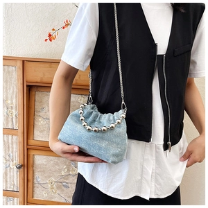 Close-up of light blue denim bucket bag featuring silver bead handle and chain strap