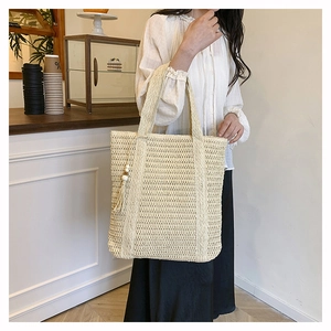 Detailed view of beige woven tote bag with a decorative wooden bead tassel accent