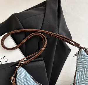 Detalle de la textura tejida azul claro y la correa de cuero marrón en el bolso retro