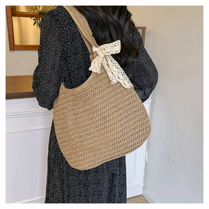 Detail of hand-woven straw tote bag with elegant lace bow decoration for beach vacations