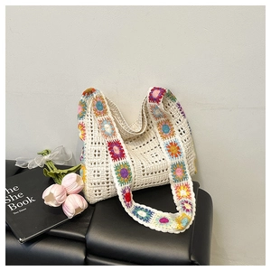 Detail of crochet tote bag with floral patterns on a leather sofa next to tulips