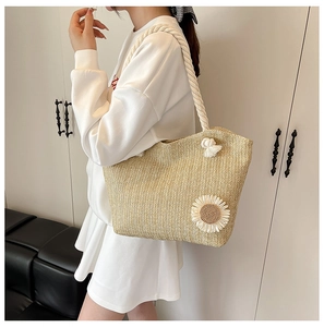 Dettaglio del fiore di sole e dei manici in corda di cotone sulla borsa di paglia beige