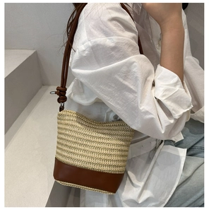 Détail d'un sac seau tressé avec base en cuir marron contrasté et bandoulière à nœuds