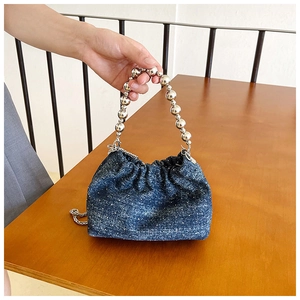 Detail of blue denim bucket bag with silver metal bead handle and drawstring closure