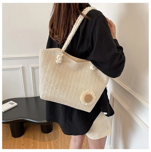 Dettaglio della borsa tote in paglia beige con decoro margherita e tracolla a corda