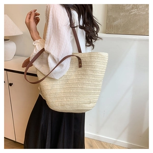 Detail of hand-woven beige tote bag with premium brown leather straps and metal rivets