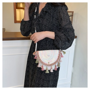 Modella con borsa a tracolla in paglia intrecciata con frange colorate in un caffè