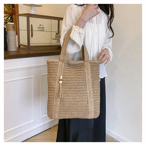 Detail of hand-woven straw tote bag with beaded tassel and natural khakitexture