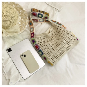Detail of beige crochet hobo bag featuring a colorful floral knit shoulder strap