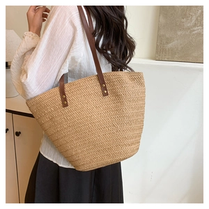 Detail of woven straw tote bag texture with brown leather strap and metal rivets