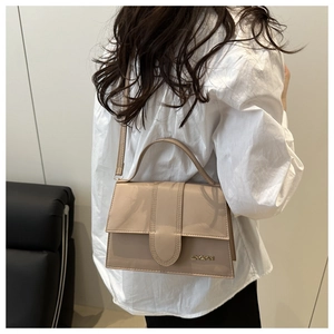 Sac bandoulière chic en cuir verni beige avec logo JINGPIN porté par un mannequin